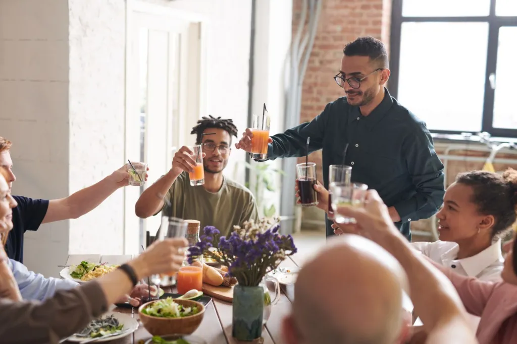 Group of friends raising their glasses in a toast around a table