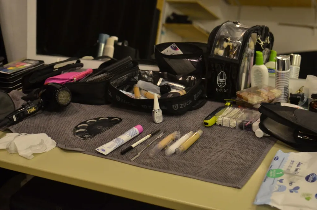 Makeup kit with brushes, pencils, palettes and products laid out on a table