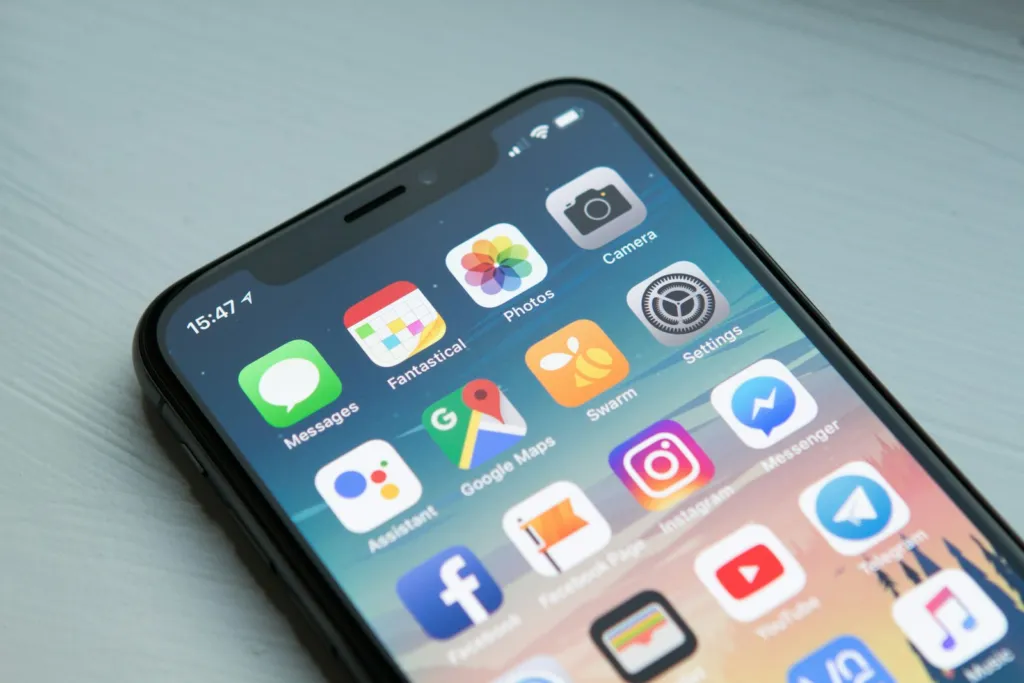 Smartphone lying on a light grey table with its home screen of app icons visible