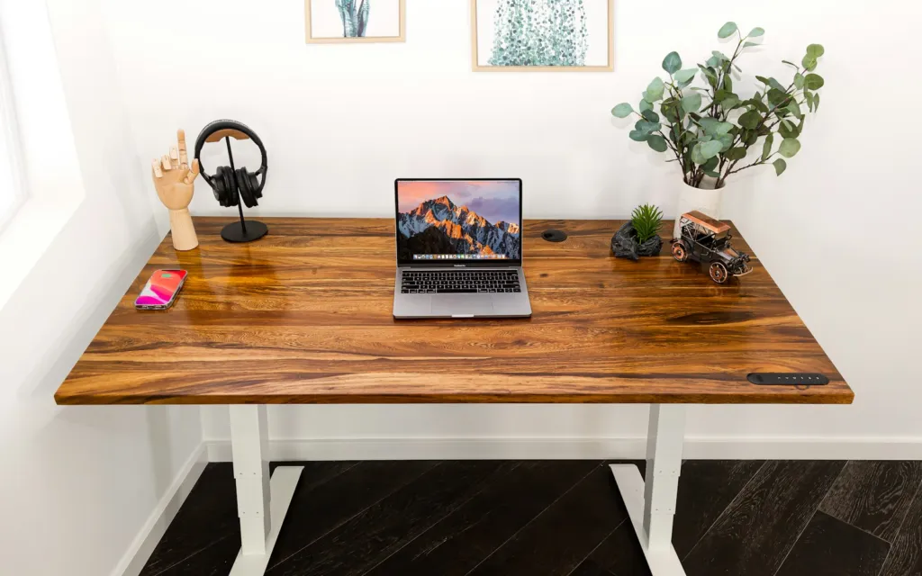 Bright home office with a wooden desk, laptop, headphones and a small plant
