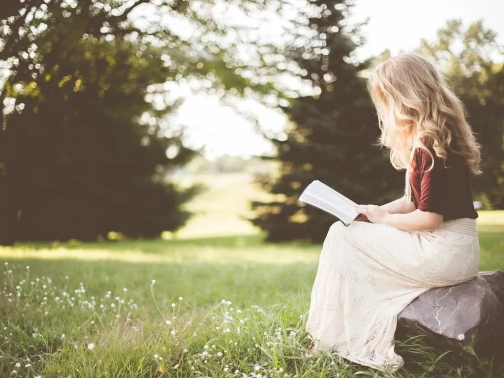 Woman reading a book outdoors in a sunny park