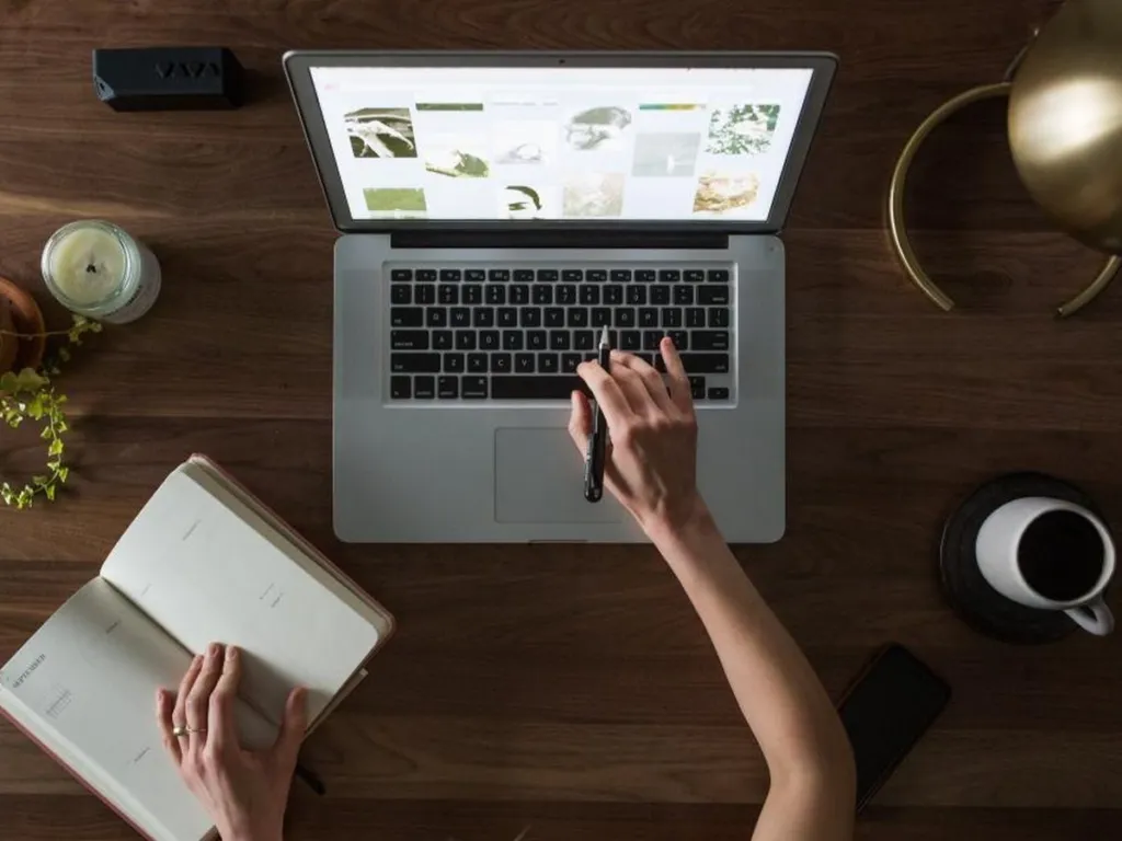 Person researching on a laptop while taking notes