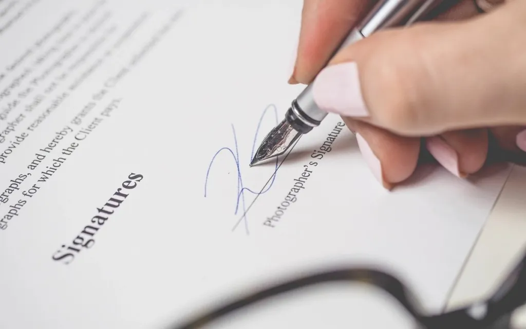 Person signing a printed contract with a fountain pen